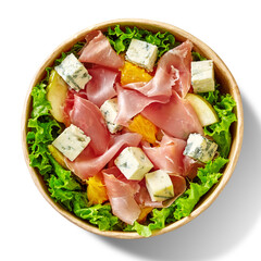 Salad with lettuce, prosciutto, blue cheese, orange, pear and mustard dressing in cardboard bowl on white