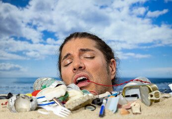 Man buried in sand on beach with rubbish
