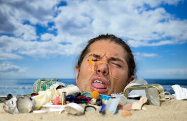 Man buried in sand on beach with rubbish