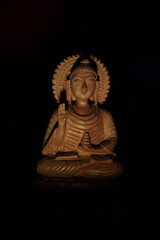 WOODEN BUDDHA STATUE IN LUMINANCE LIGHTING.
