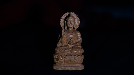 WOODEN BUDDHA STATUE IN LUMINANCE LIGHTING.