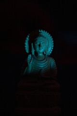 WOODEN BUDDHA STATUE IN LUMINANCE LIGHTING.