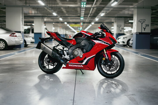 Side view photo of a Honda CBR1000 fireblade racing motorcycle in a parking lot.