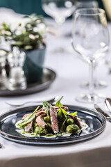 Creatively cooked beef flank steak with spinach gnocchi served on a ceremonially prepared table in the hotel restaurant