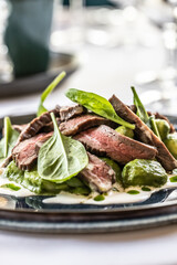 Creatively cooked beef flank steak with spinach gnocchi served on a ceremonially prepared table in the hotel restaurant