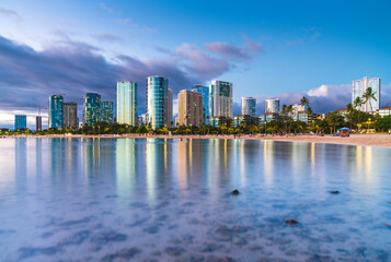Fototapeta na wymiar hawaii beach with city skyline at sunset.