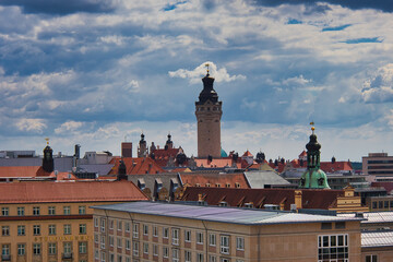 Fototapeta premium Blick über die Dächer der Innenstadt mit dem markanten Turm des Neuen Rathauses unter dramatischem Wolkenhimmel, Leipzig, Sachsen, Deutschland
