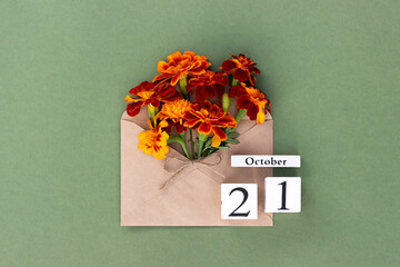 October 21. Bouquet of orange flower in craft envelope and calendar date on green background. Minimal concept Hello fall. Template for your design, greeting card
