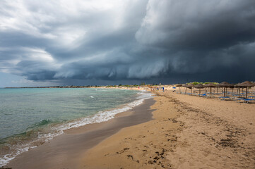 Beautiful sunny beach with black and stormy clouds in the sky in Sicily