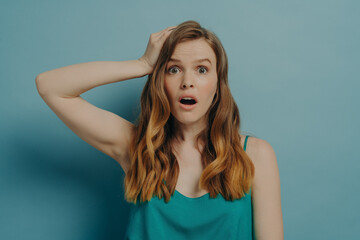 Fototapeta premium Surprised and shocked caucasian woman being amazed with wide open eyes and mouth, isolated on blue
