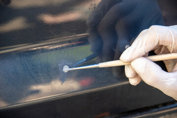 The car painter pointwise brings the primer with a brush into the paint layer.
