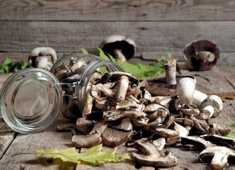 Dry mushrooms on a rustic vintage wooden background, in a glass jar and in bulk. Drying and harvesting mushrooms for autumn and winter. The concept of natural organic eco products.