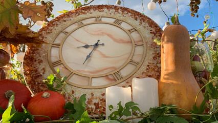 Autumn garden home decoration composition with clock, pumkins, candles and apples. Fall yard arrangement on the table or other zone