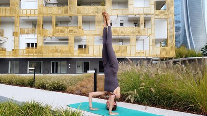 21 year old girl performs yoga gymnastic sport near modern downtown skyscrapers - relax and...
