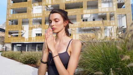 21 year old girl performs yoga gymnastic sport near modern downtown skyscrapers - relax and meditation in Milan city - fight the hustle and bustle of urban life with physical and mental exercises