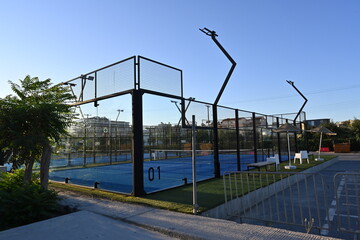 An enclosed blue court for padel with construction created by mesh and the glass back walls. Padel...