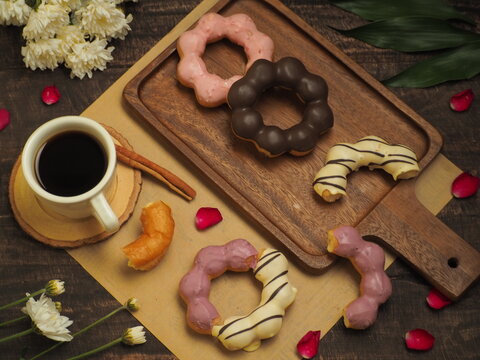 A set of donuts with black coffee on a wood table