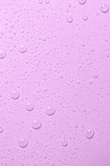 Drops of micellar water or cosmetic tonic on a pink background. Close-up, macro photography