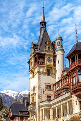 Fototapeta premium Peles castle tower close-up view and Carpathian mountains snow peaks, Sinaia, Transylvania, Romania