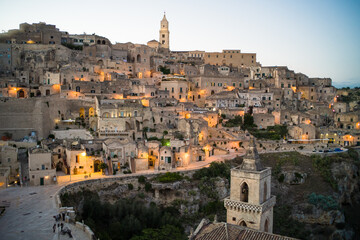 Naklejka premium view after dark of old stone houses and churches on the slopes of the gorge in the historic center of the old town of Matera illuminated by street lamps. Cascade buildings of the old town with rocks 