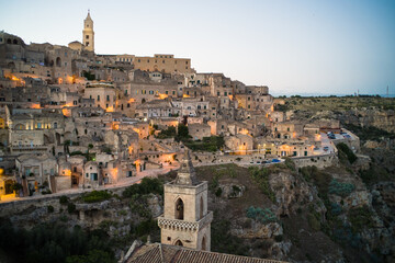 Fototapeta na wymiar view after dark of old stone houses and churches on the slopes of the gorge in the historic center of the old town of Matera illuminated by street lamps. Cascade buildings of the old town with rocks 