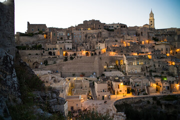 Naklejka premium view after dark of old stone houses and churches on the slopes of the gorge in the historic center of the old town of Matera illuminated by street lamps. Cascade buildings of the old town with rocks 