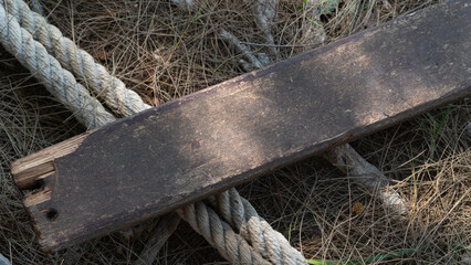 Wooden board and thick rope rope on dry grass