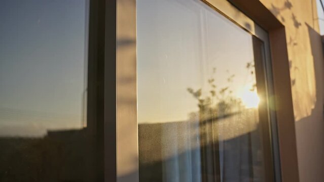Sunset or sunrise as sun reflects on dusty windows or glass doors of house. Flare hits the glass as sun is setting or rising in early morning or sundown. Hot day. Green solutions for solar energy
