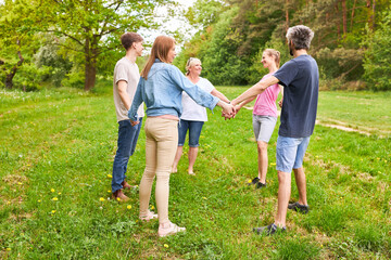 Young people stand in a circle holding hands