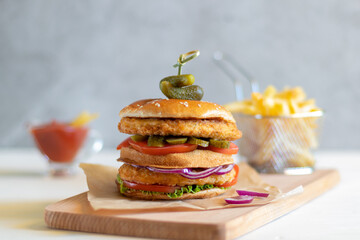 Chicken burger with fries and ketchup on a light background