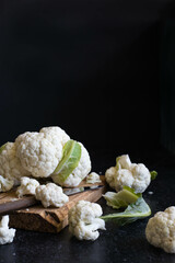 Sliced cauliflower on a cutting board on a dark background. Side lighting. Close-up. Selective focus.