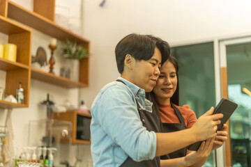 Young attractive female LGBT owners use a tablet to check any online order for their coffee shop delivery service. Startup business LGBT couple uses technology to provide online coffee service
