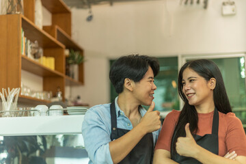 Young LGBT couple takes a break to take care each other in their startup coffee shop. Romantic time of a young LGBT owners in front of coffee bar