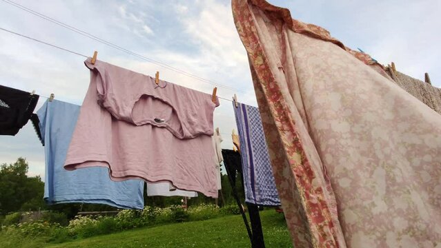 Different clean clothes drying after washing on the rope outdoors. 