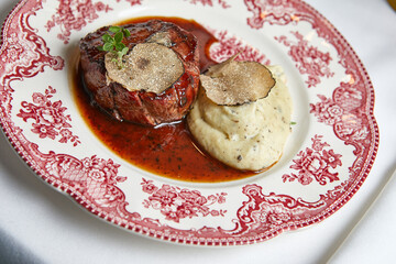 beef steak with mashed potatoes in sauce on a beautiful porcelain plate