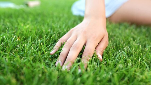 Woman touching fresh grass on green lawn, closeup