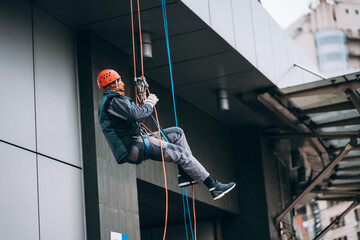 Industrial climber in uniform and helmet rises
