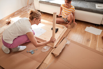 Mother and daughter assembling new furniture - moving in into a new home.