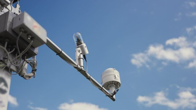 Meteorological instruments for weather condition data measurements on antenna. Radiometer or anemometer and light meter and rain gauge sensor located on top of pole with blue sky. Data on wind and sun