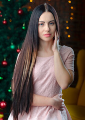 Portreit of beautiful woman near the christmas tree lights background. Healthy long hair style. happy new year and Christmas concept. 