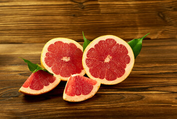 Grapefruit halves and slices with leaves on a wooden background. Beautiful photo wallpaper of fruit.