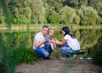 Beautiful happy Ukrainian family in the forest in summer. Mom, dad and son 2 years old in the forest.