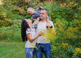 Beautiful happy Ukrainian family in the forest in summer. Mom, dad and son 2 years old in the forest.
