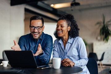Smiling business people having a meeting together, over the laptop.