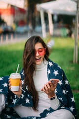 Young woman in the park with a paper glass of coffee