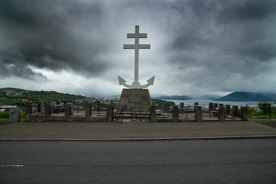 Memorial cross in Greenock against a cloudy sky with the town in the background on a gloomy day