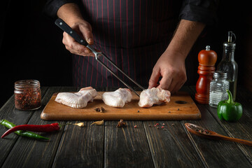 The chef prepares chicken nugget with raw chicken wings in the kitchen. Space for advertising on a dark background