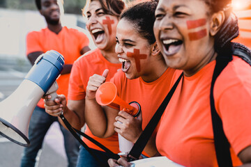 Females football fans exulting while watching soccer game at stadium - Women with painted face and megaphone encouraging their team - Sport entertainment concept