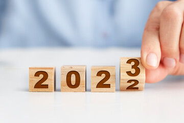 New year concept with wooden blocks, woman flipping wooden block to make it 2023