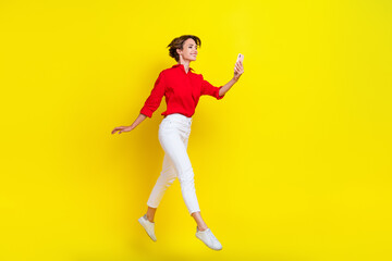 Full length photo of crazy carefree person jumping hold use telephone isolated on yellow color background